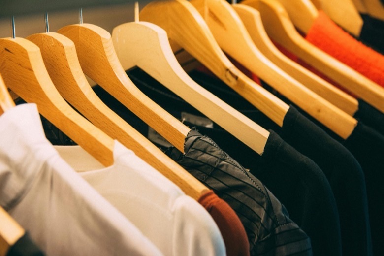 A rail of apparel hanging on wooden hangers