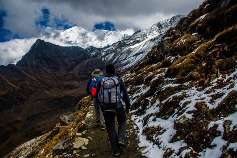 Hikers with backpacks on a snow-covered mountain trail